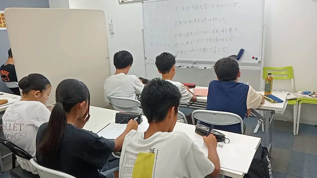 ホワイトボードの英文を見ながら演習する生徒たち